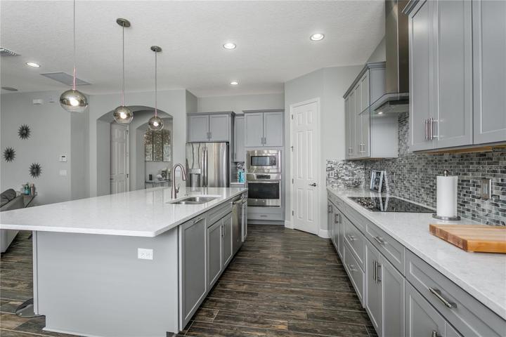 Kitchen has raised-panel wood cabinetry w/crown molding, glass tile backsplash, STAINLESS STEEL APPLIANCES., built-in WALL OVEN and microwave.
