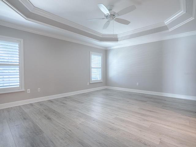 PRIMARY BEDROOM WITH CROWN TRIMMED TRAY CEILING, PLANTATION SHUTTERS, THE SAME LAMINATE FLOORING AS THE GUEST ROOMS AND CROWN MOLDING.