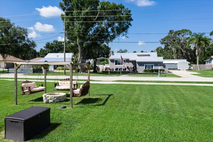 Oversized green space with a social swing area and fire pit allow for conversations and family fun for that ultimate relaxation and resort feel.  The black box holds the new irrigation well pump, which is used for all exterior irrigation.