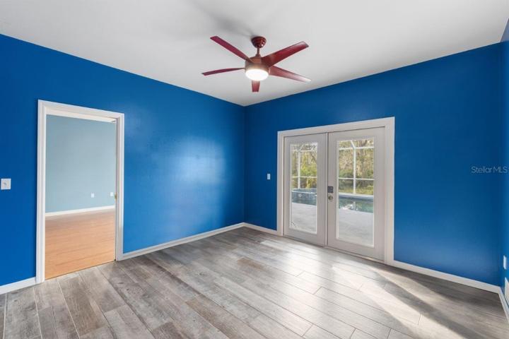 Office/ Den located off the kitchen and family room features porcelain wood-look tile, and French doors out to the screened-in lanai and pool!