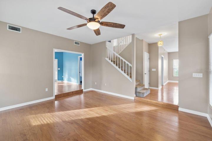 Living room featuring a wood burning fire place, wood floors, and 10' ceilings.