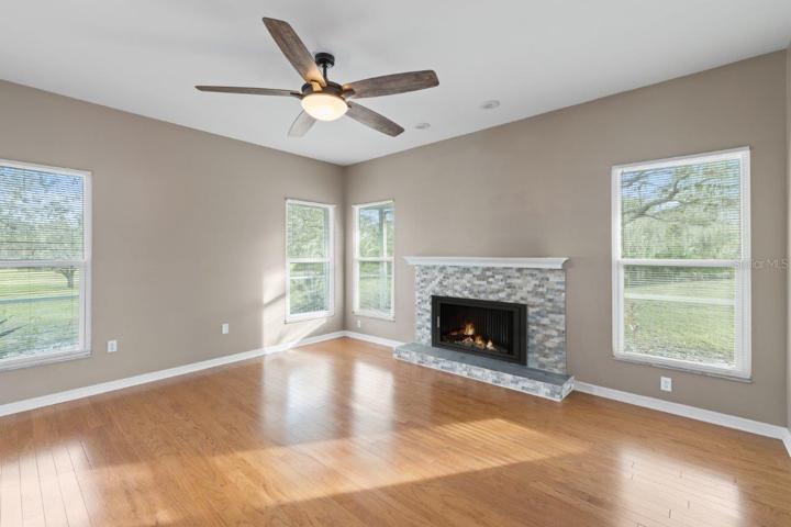 Living room featuring a wood burning fire place, wood floors, and 10' ceilings.
