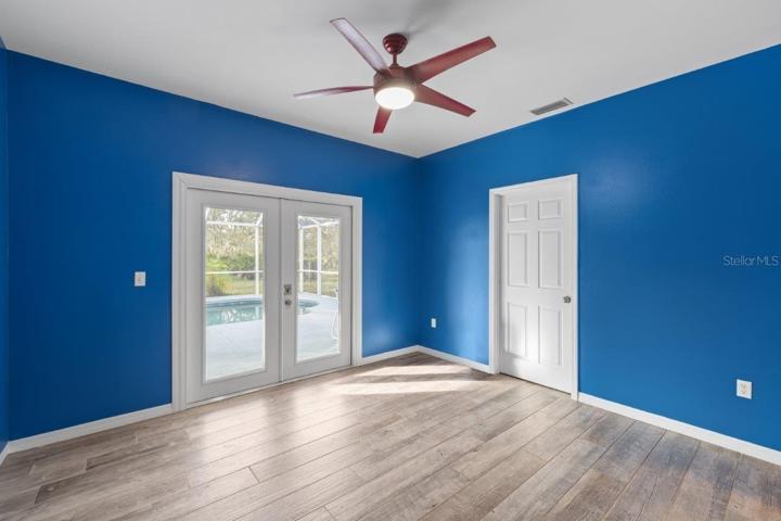 Office/ Den located off the kitchen and family room features porcelain wood-look tile, and French doors out to the screened-in lanai and pool!