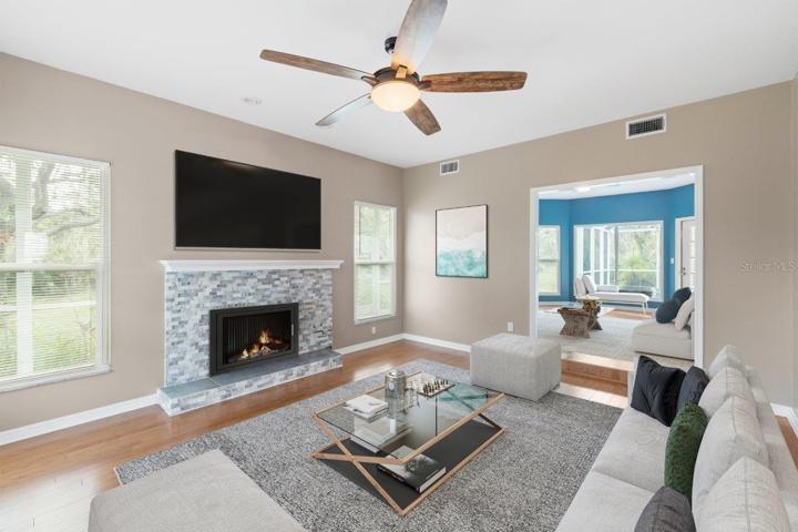 Living room featuring a wood burning fire place, wood floors, and 10' ceilings.