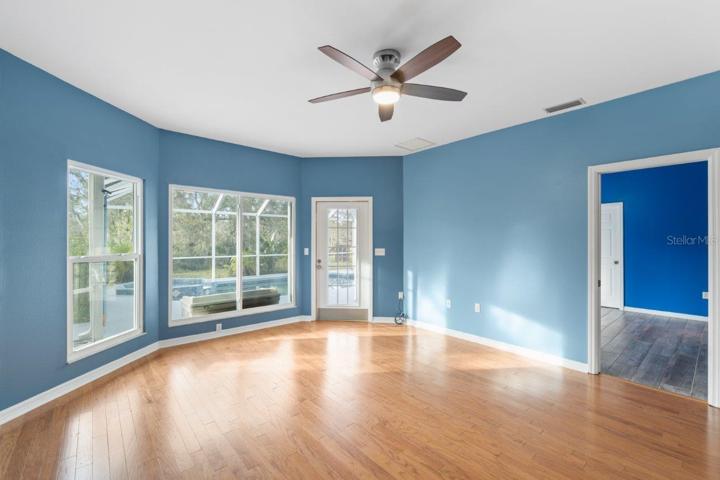 Spacious Family Room featuring Wood flooring, extended bay windows, and direct access to the screened-in lanai