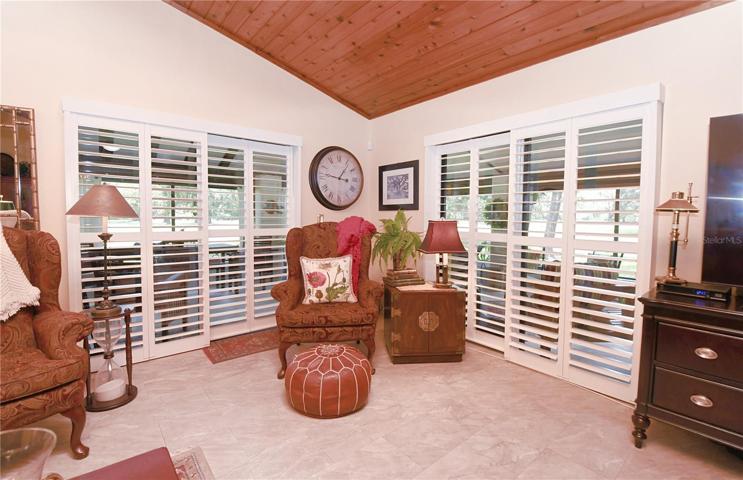 Sliding glass doors with plantation shutters lead to the screened in porch.