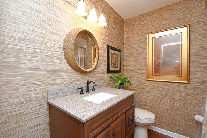 The guest bathroom with chic grasscloth wallpaper, continues the aesthetic of understated luxury.