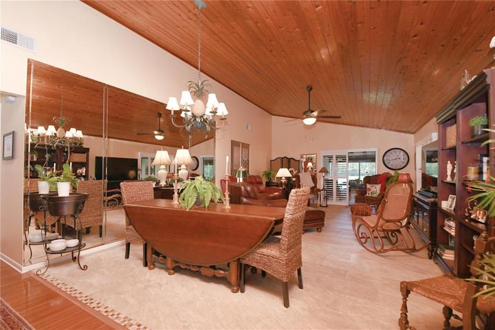 The expansive living and dining areas exude warmth, crowned by wood plank vaulted ceilings that create an inviting atmosphere while also minimizing sound reflections.