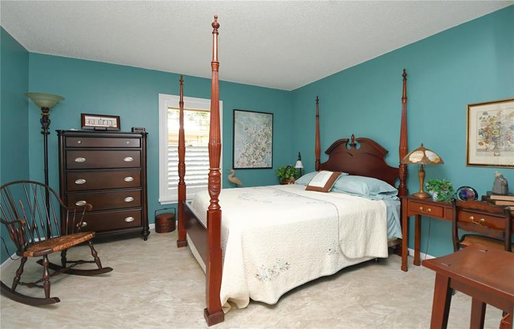 The second bedroom, dressed in neutral plank ceramic tile flooring, a built-in closet with raised panel bifold doors,