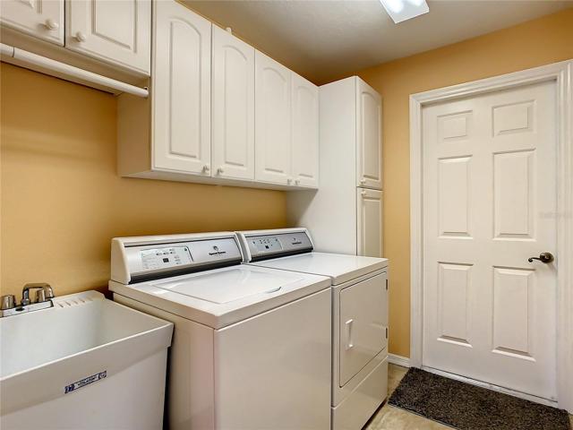 Inside utility room has laundry sink and built in cabinets and hanging rod.