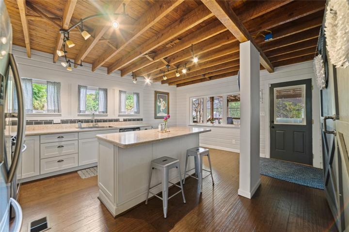 The kitchen has been completely renovated but fits the style of this home perfectly while delivering a gorgeous WOOD CEILING along with modern quartz counters, stainless steel appliances (including a GAS STOVE!), great natural light and a large ISLAND with breakfast bar seating for casual dining!