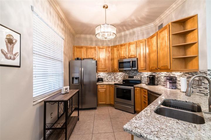 Kitchen with upgraded appliances, counter top, sink, faucet, backsplash, under counter lighting and ceiling light.