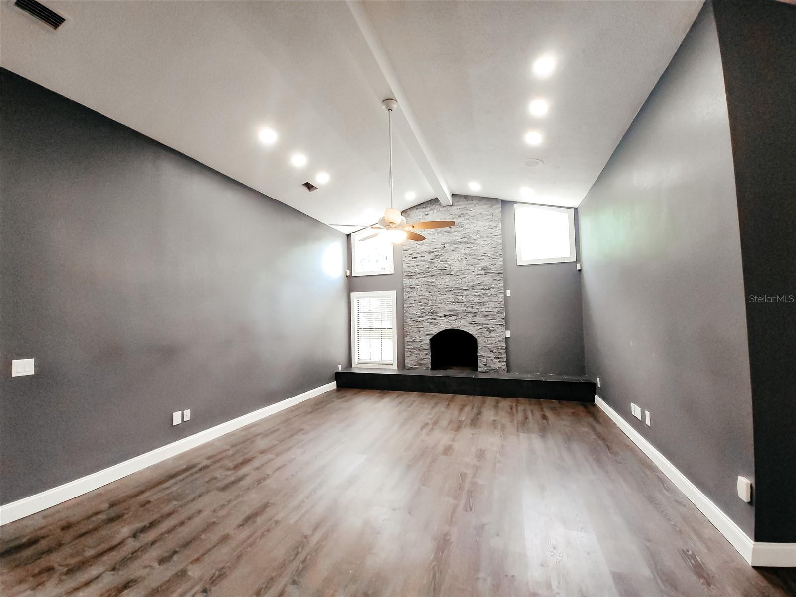 Great Room with vaulted ceilings and a stone fireplace centerpiece
