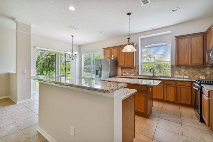 Breakfast bar overlooking the L-shaped kitchen with 42" cabinets, island, and SS appliances