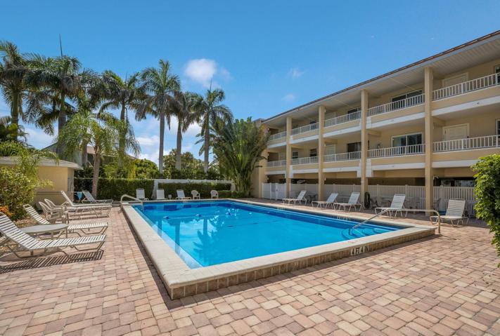 Private heated community pool w/ lush landscape, outdoor shower, and vinyl fence