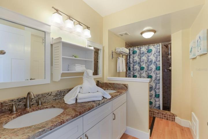 Primary bathroom w/ granite counters, dual vanity, stand up shower, and walk in closet