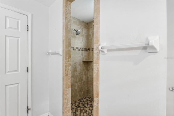 Walk in shower with frameless glass door and dual shower head.