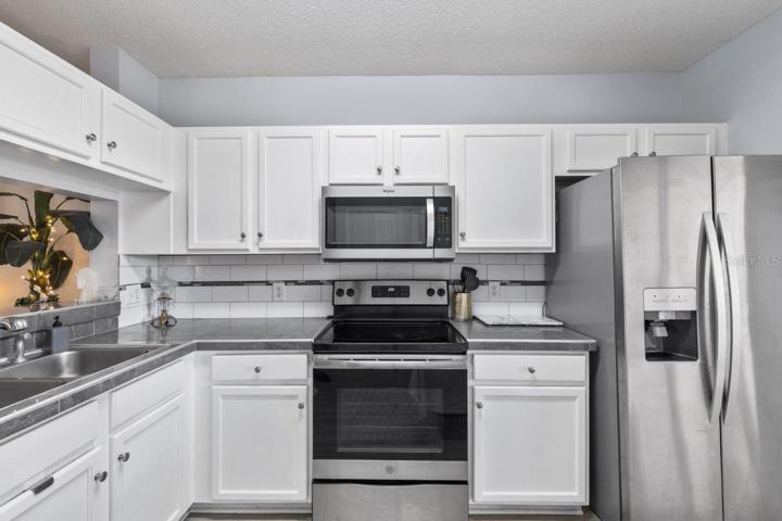 Open Kitchen featuring renovated tile countertops, wood look tile flooring, stainless steel appliances, and direct access to the back lanai