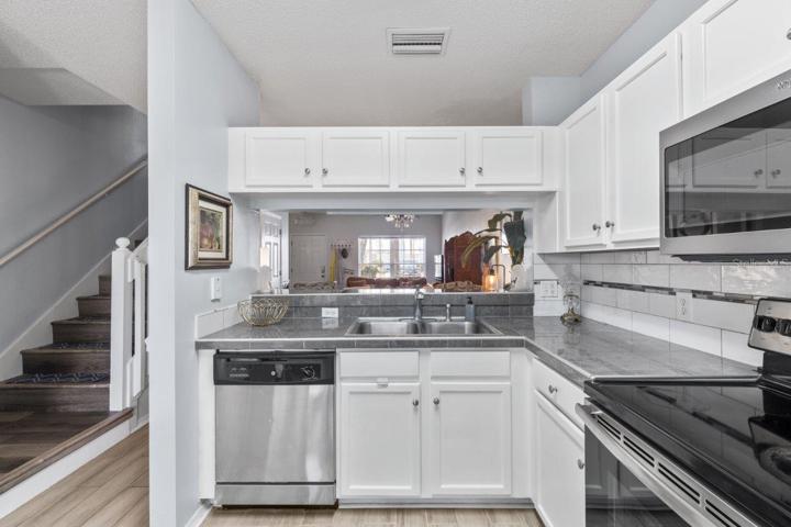 Open Kitchen featuring renovated tile countertops, wood look tile flooring, stainless steel appliances, and direct access to the back lanai