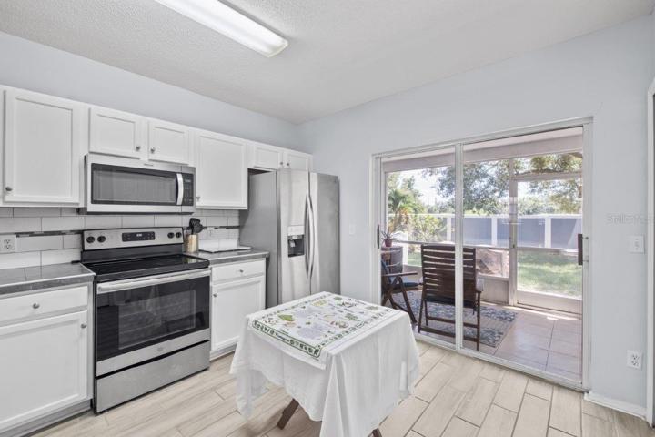 Open Kitchen featuring renovated tile countertops, wood look tile flooring, stainless steel appliances, and direct access to the back lanai