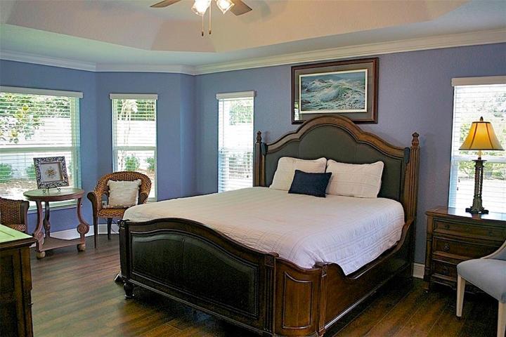 Master bedroom with elegant king bed resting on walnut laminate flooring for easy care. Plenty of light yet a private rear view night or day.