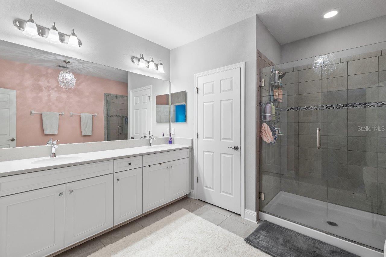 Owners en-suite bathroom featuring dual sinks, walk-in glass enclosed shower, and water closet