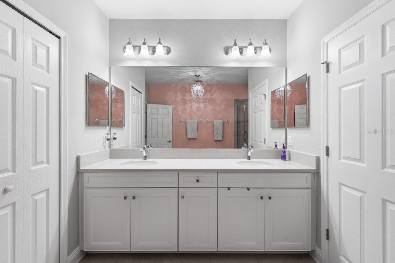 Owners en-suite bathroom featuring dual sinks, walk-in glass enclosed shower, and water closet