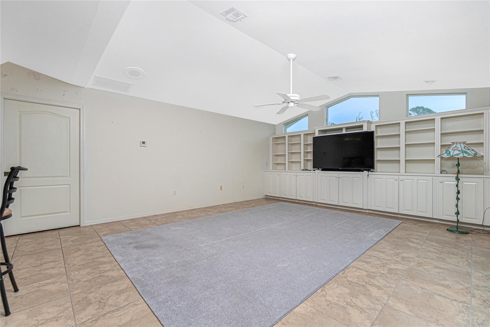The family room with a ceiling fan, and clerestory windows is situated just off the kitchen.