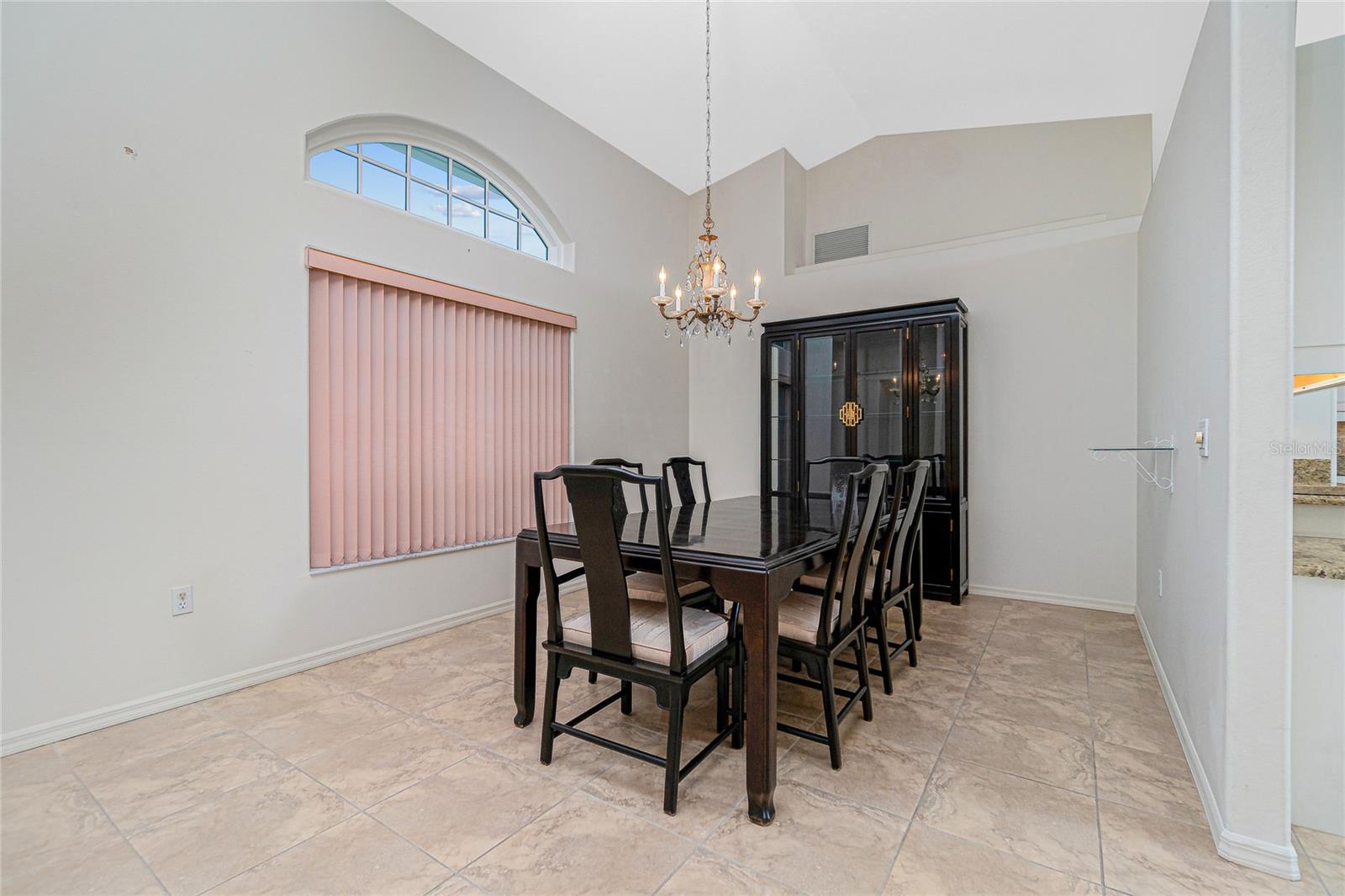 The formal dining room has tiled flooring, chandelier and windows looking out to the front of the home.
