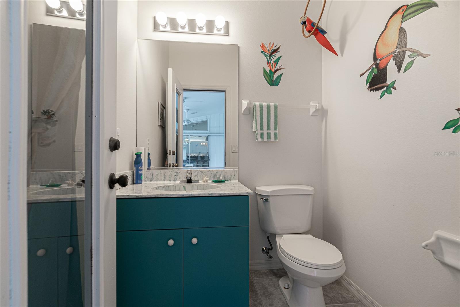 Poolside half bath with single vanity and tile flooring.