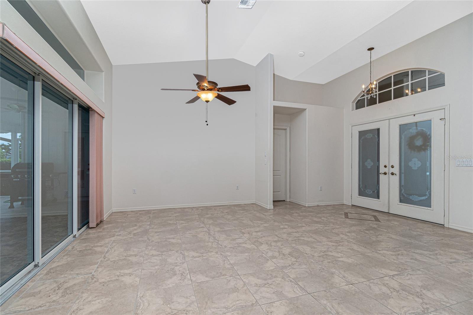 The living room has tiled flooring, cathedral ceiling, ceiling fan and sliding glass doors to the lanai.