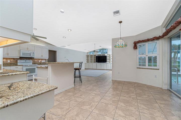 The fully updated and open kitchen includes recessed lighting, granite counters, tiled flooring, newer appliances, built-in desk, and a breakfast nook with sliding doors to the lanai.
