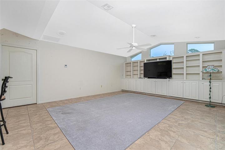 The family room with a ceiling fan, and clerestory windows is situated just off the kitchen.