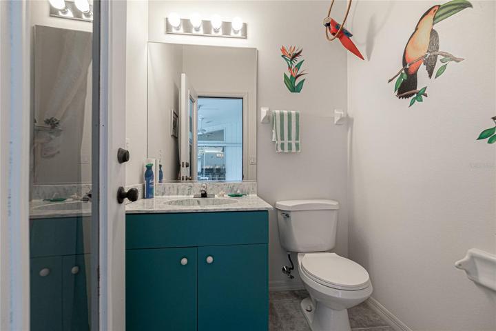 Poolside half bath with single vanity and tile flooring.