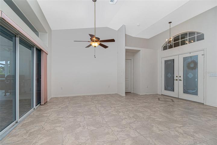 The living room has tiled flooring, cathedral ceiling, ceiling fan and sliding glass doors to the lanai.