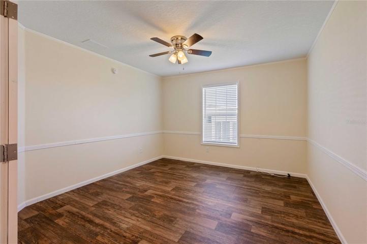 Den/office has chair railing, luxury vinyl, ceiling fan, and French double doors.