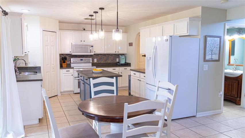Updated lighting in the kitchen which features a center island, two pantry closets, and appliance storage.