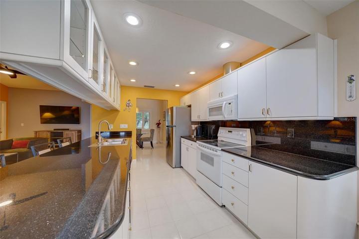 The light and bright galleystylekitchen is well-equipped and features white cabinets, beautiful dark granite countertops, and a breakfast bar that overlooks the familyroom