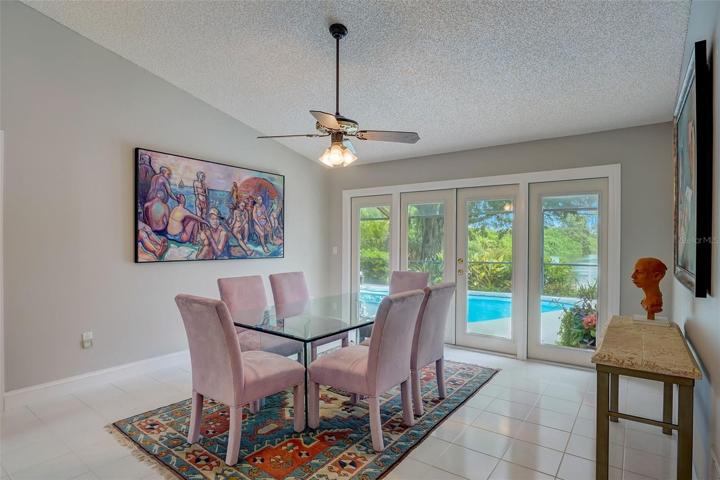 The dining room, or what could also serve as a living room, has a wall of windows that frame the beautiful outside scenery and French doors leading out to the pool area