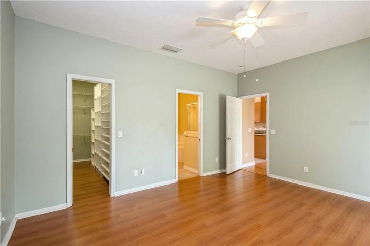Glimpse of walk in closet with built ins and bathroom.