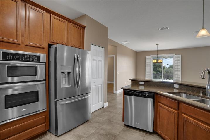 chefs kitchen with stainless steel appliances. built in oven/microwave with granite countertops.