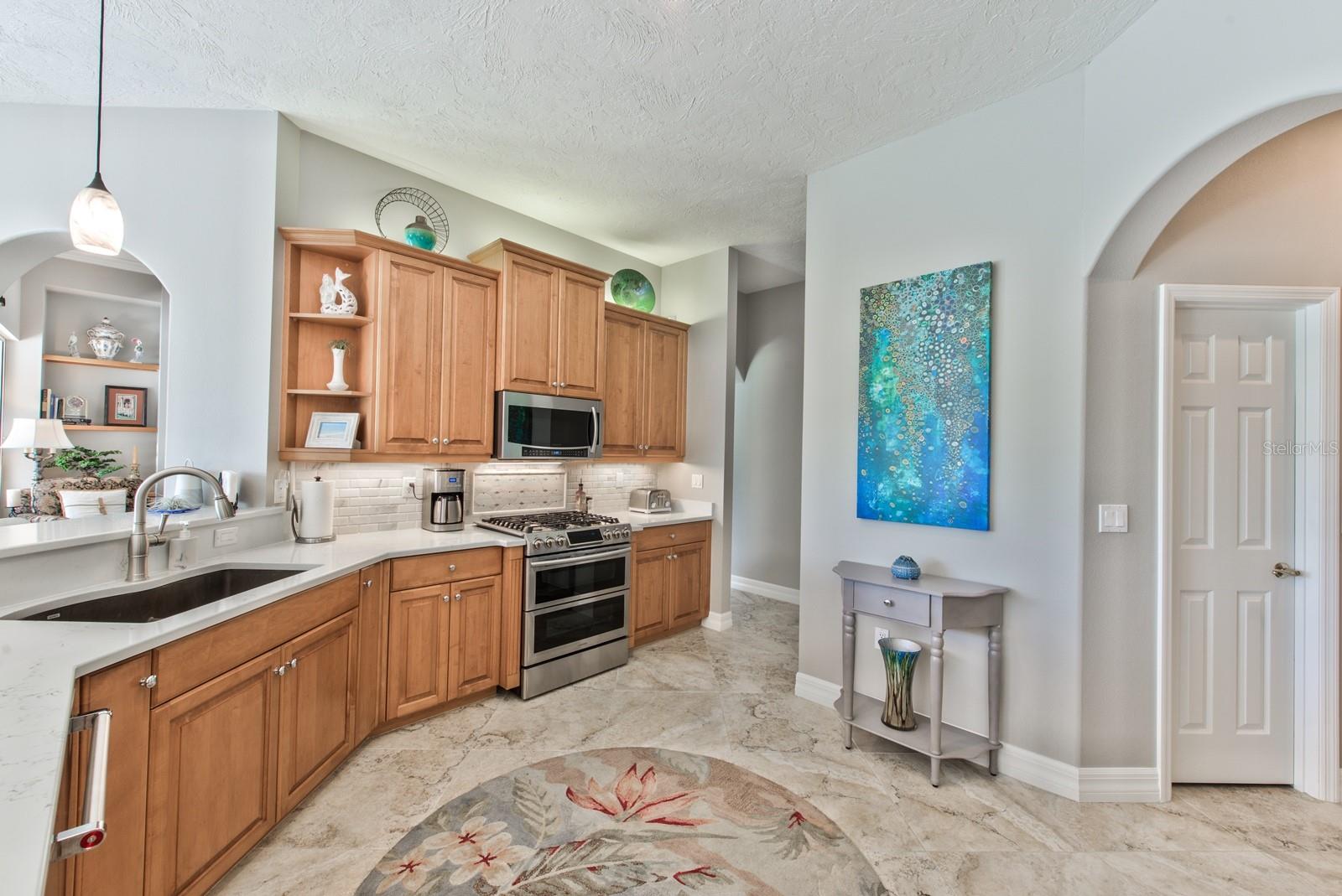 Designer pendant lighting, over and under cabinet lighting, a 5 burner gas range with dual oven &amp; convection settings and double pantries are found in the chef's kitchen.