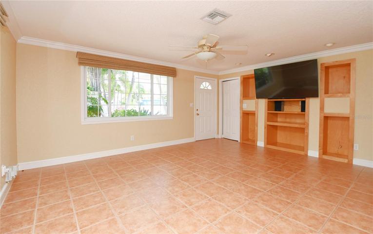 The great room features ceramic tile flooring, a neutral color palette and a ceiling fan.