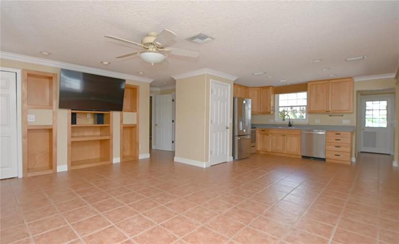 The great room features a wall mounted flat screen tv and build in shelves.
