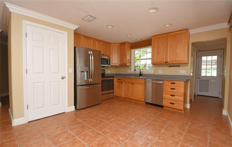 The kitchen is functional and stylish and is outfitted with a premium suite of GE stainless steel appliances, including a French door refrigerator with water dispenser and ice maker, an electric range, and a microwave and dishwasher.  A window above the double stainless steel sink offers mesmerizing views of the pool and shimmering waters beyond.