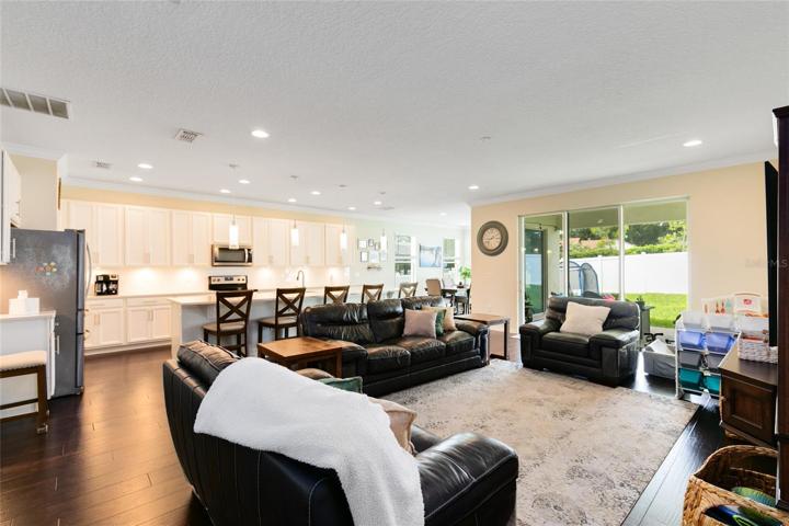 An abundance of natural light embraces the open floor plan seamlessly connecting the living room, kitchen, and dining areas.