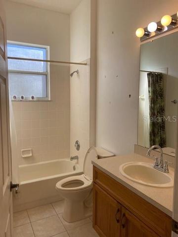 GUEST BATHROOM, TILE FLOORS AND TUB WITH SHOWER.
