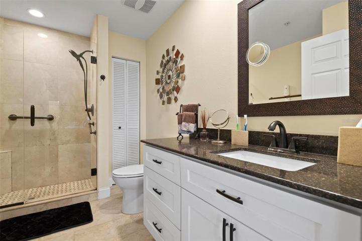 Master bath with white Shaker cabinets, granite counters and frameless glass shower