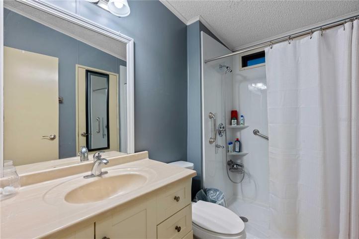 Guest bathroom has updated vanity, step-in shower, and high toilet.