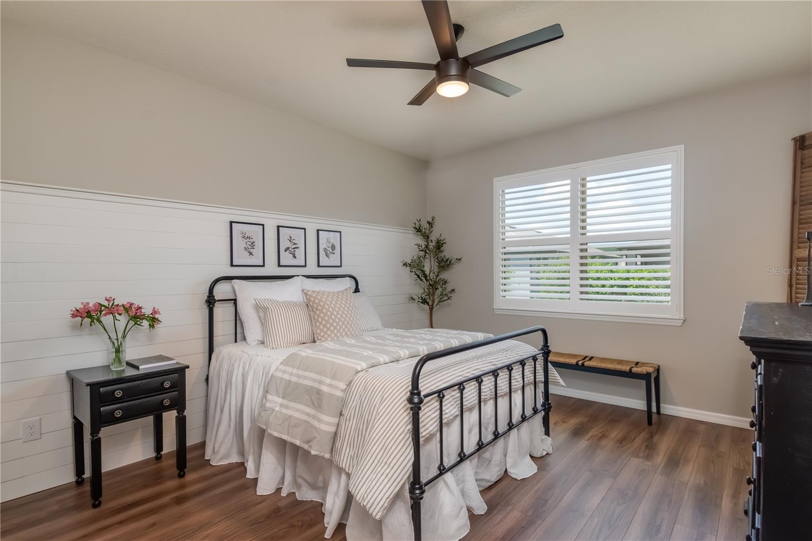 Large primary bedroom with custom shiplap wall feature, LVP flooring &amp; plantation shutters